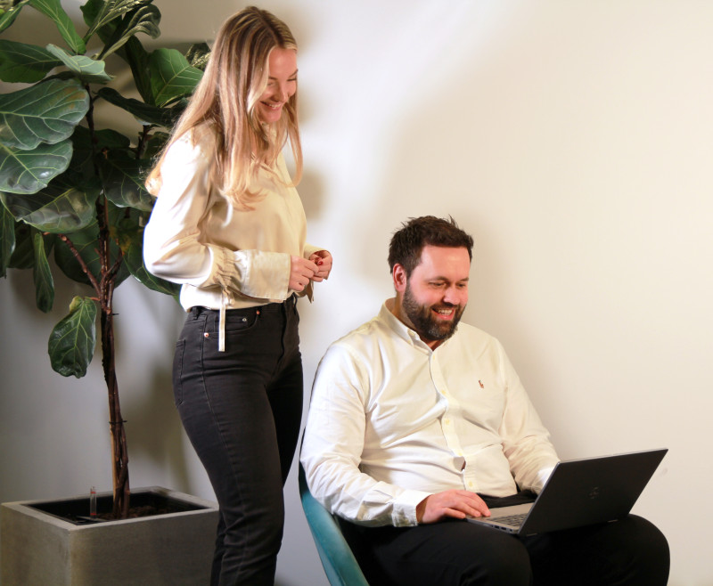 Bjørnar is sitting in an armchair working, elsa is standing next to him. Bjørnar sitter i fåtölj och arbetar, elsa står bredvid.