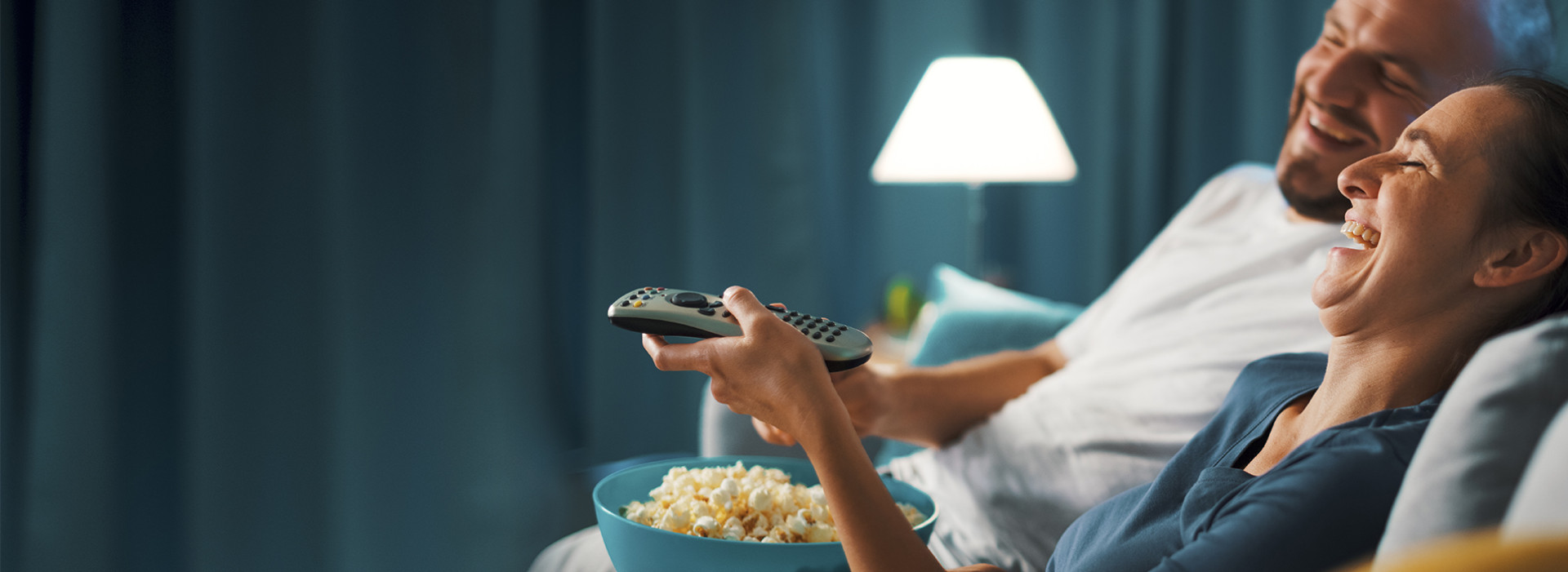 A happy couple watching TV and eating popcorn. Ett glatt par ser på tv och äter popcorn.