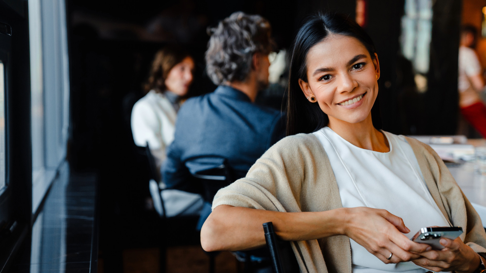 Brown-haired woman sitting down and smiling. Brunhårig kvinna sitter ner och ler.