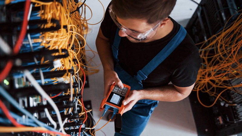 A technician with measuring instruments in a server room. En tekniker med mätinstrument i ett serverrum.