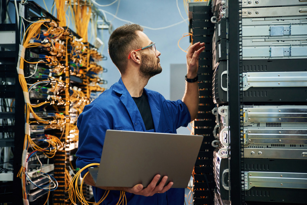 Technician with computer in server room. Tekniker med dator i serverrum.