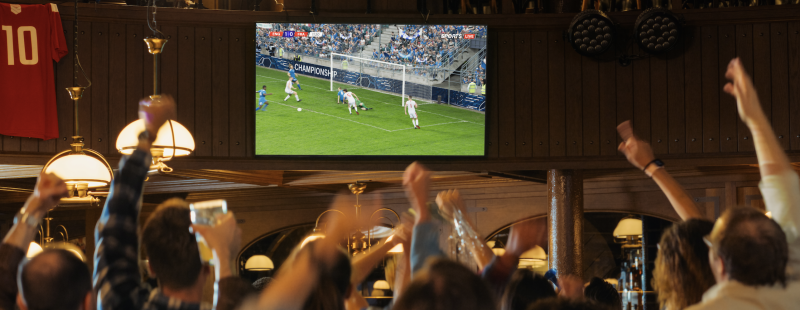 People in a bar watching a football match. Folk i bar som tittar på fotbollsmatch.