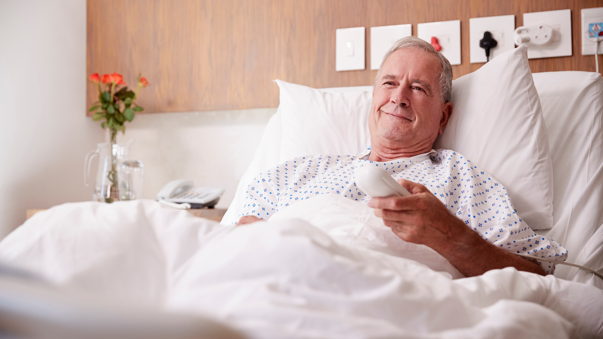 Elderly man watching TV in hospital bed. Äldre man ser på TV i sjukhussäng.